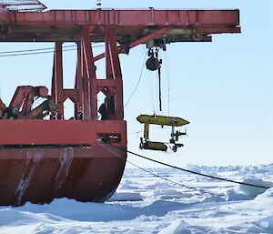 A yellow machine is lowered from the ship.