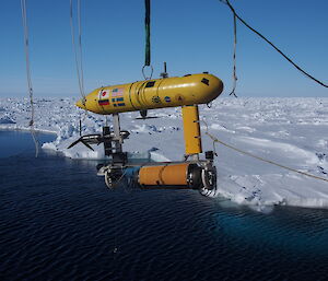 Yellow Autonomous Underwater Vehicle (AUV) suspended above the water.