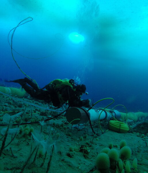 A diver manoeuvres a thruster tube on the sea floor during an ocean acidification experiment.