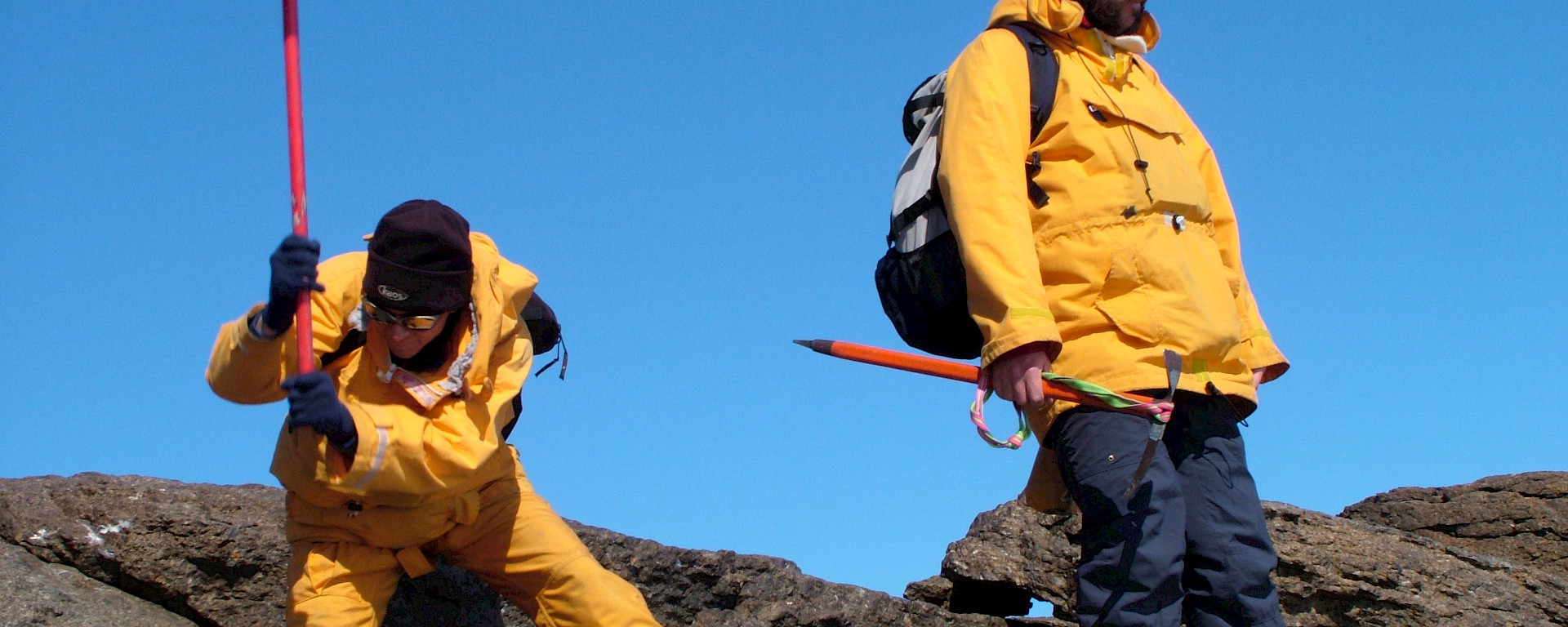 Geologist wielding pick axe, other standing nearby