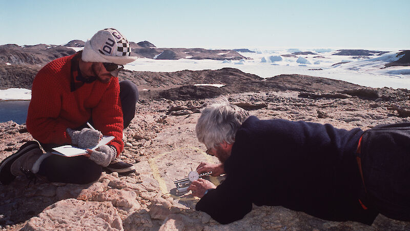 Two geologists with measuring tools and a note book