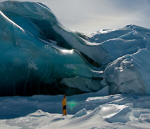 Expeditioner standing in front of a grounded jade iceberg