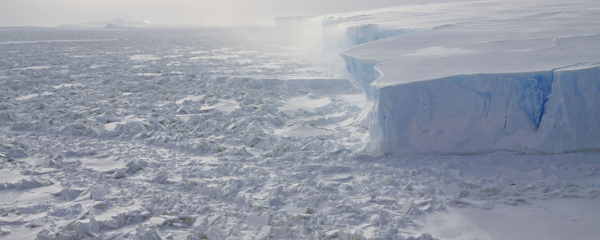 Ice cliffs above an uneven ice surface, viewed from the air.