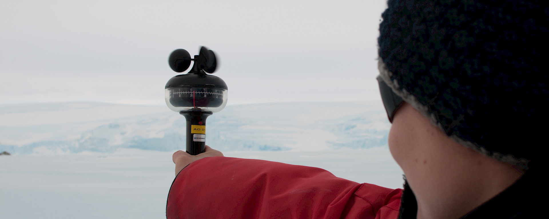 Expeditioner holding instrument at arm’s length to measure wind speed and direction