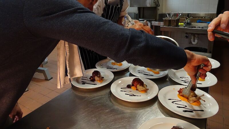 Two people plating up dinner in the Mawson kitchen