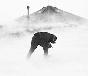 Expeditioner bent over in the face of wind and blowing snow