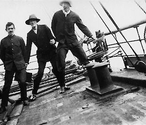 Four expeditioners standing on the heavily-leaning deck of the Aurora