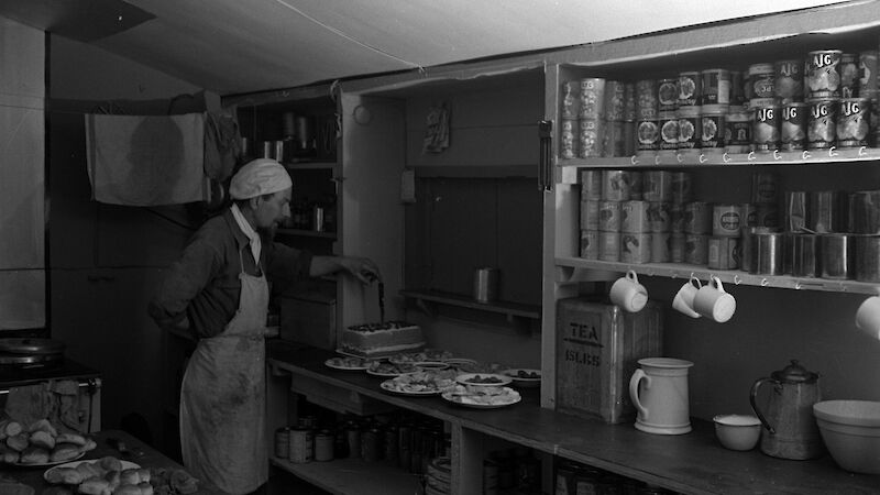Black and white image of cook at the kitchen servery bench