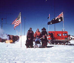 The traverse party stand in front of the vehicle and flags at Vostok