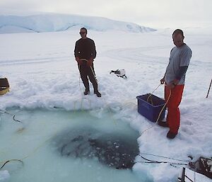 Two expeditioners standing at dive hole monitoring operations