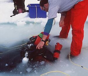 Expeditioner assisting diver out of the water