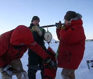 Three expeditioners weighing penguins