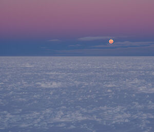 A full moon over icy sea