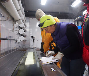 Three scientists bend over a beach looking at the sample.