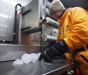 Scientist cuts a long cylindrical ice core into shorter sections. with a blade.