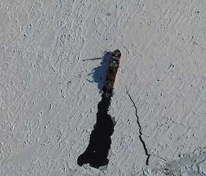 Aerial shot of the ship moving through ice with a line of clear water behind