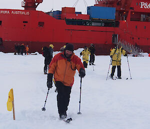 Several people on cross-country skis heading away from the ship