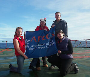 The four young scientists hold up their flag looking very excited about their trip to Antarctica.