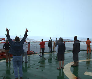 Expeditioners waving from the heli-deck of the ship