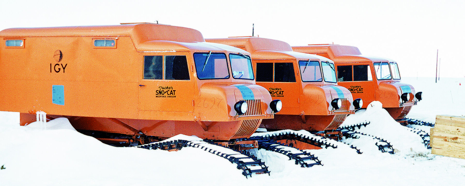 Orange oversnow vehicles in a line.