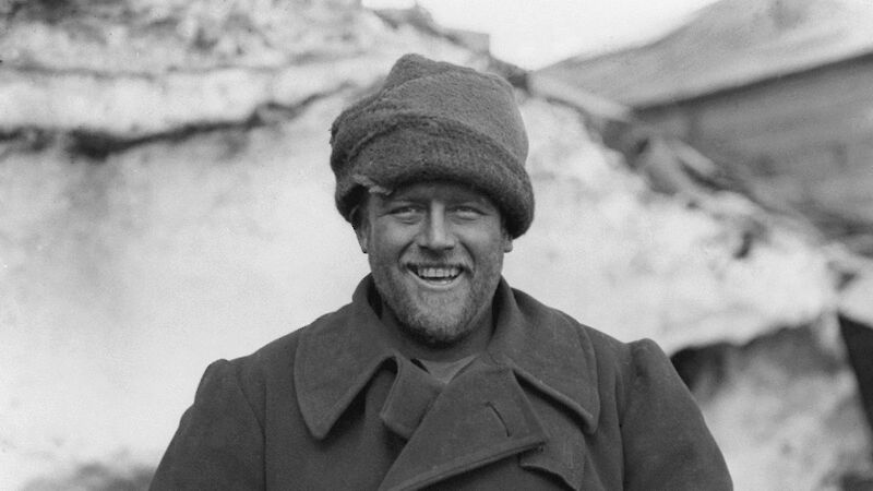 Black and white image of man in great coat and woollen beanie
