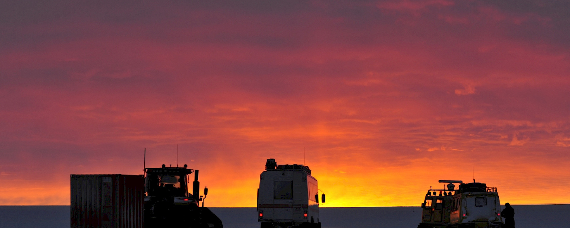 Vehicles on the the ice at sunset