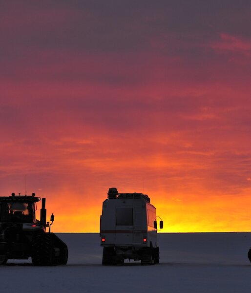 Vehicles on the the ice at sunset