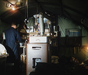 Expeditioners cooking and eating in field hut.