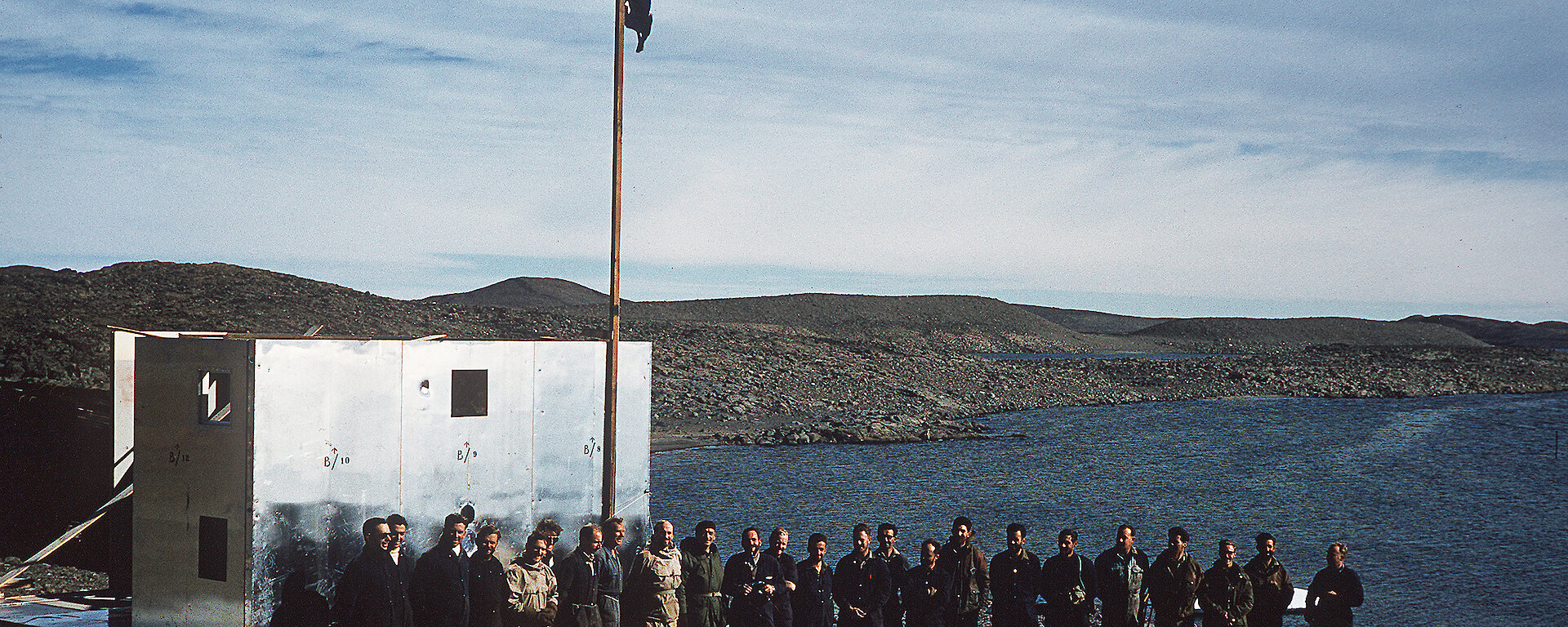 Group of men posing beside flag and buildings at Davis