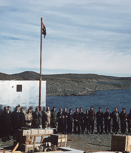 Group of men posing beside flag and buildings at Davis