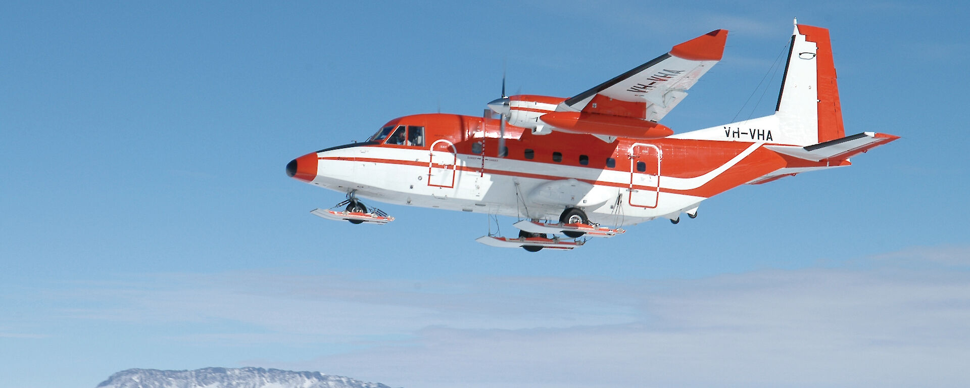 Little red plane int the sky over the ice.