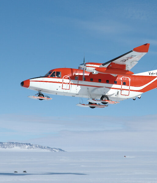 Little red plane int the sky over the ice.