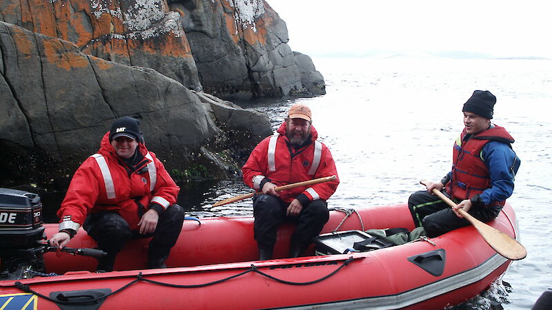 Three men sitting in a rubber boat