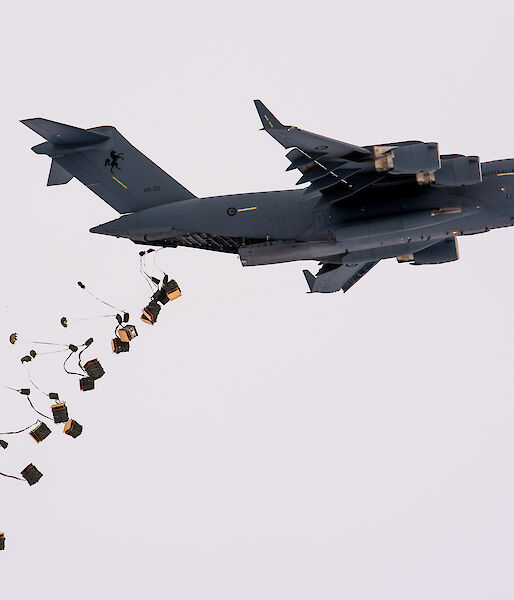 Pallets of supplies attached to parachutes drop from the tail end of a C-17A aircraft.