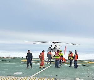 BK-117 helicopter on helideck of ship with deck officers and crew