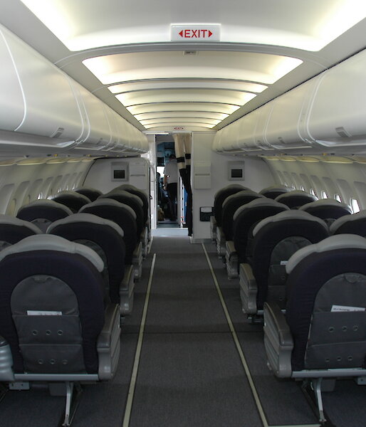 Rows of seats inside a small plane, three on each side with a row in the middle