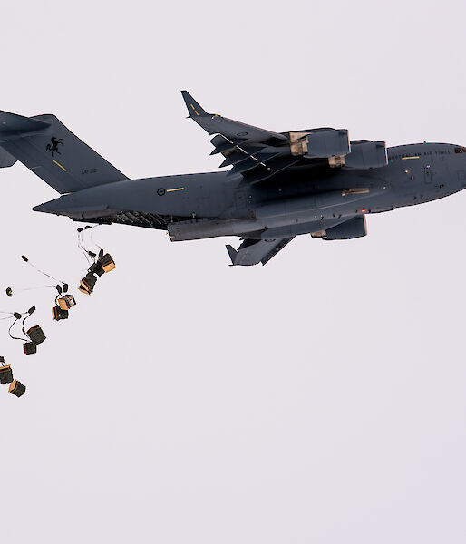 Pallets of supplies attached to parachutes drop from the tail end of a C-17A aircraft.