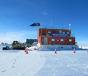 Orange building in the sun with flag flying alongside.