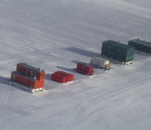 Green and red sheds made out of shipping containers on the ice at Wilkins Runway.