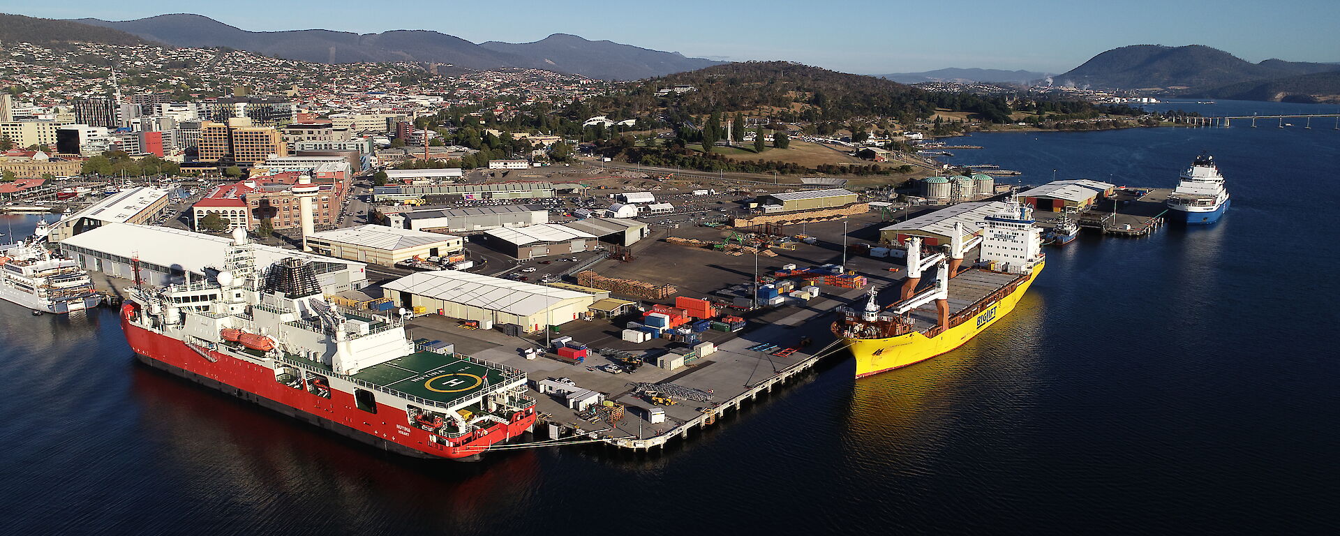 An aerial drone photo of three ships in the port of a city.