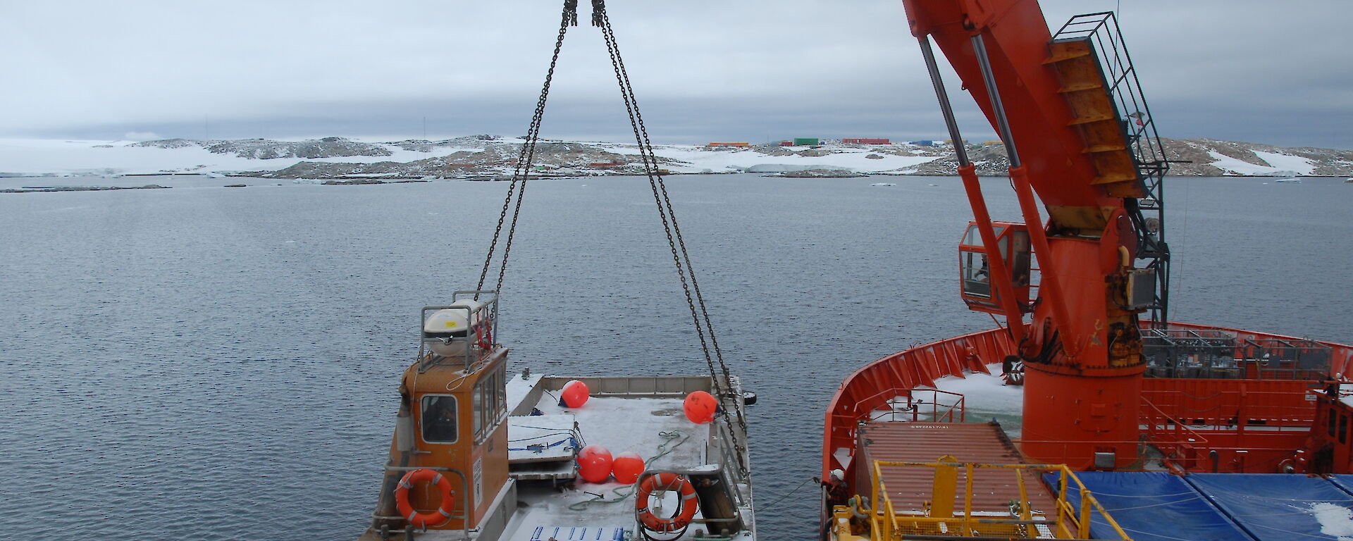 Barge suspended on a cable from a crane over the side of a ship