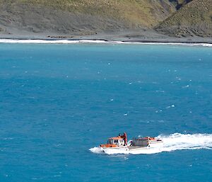 The LARC shows its use as a boat as it speeds across the water with Macquarie Island in the background