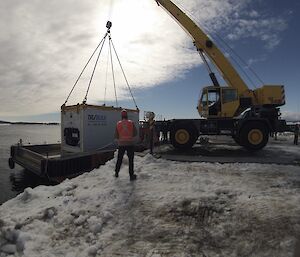 A crane at Mawson lifts a shipping container from the barge during the over water resupply.