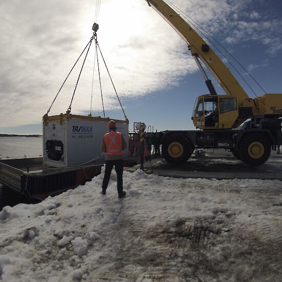A crane at Mawson lifts a shipping container from the barge during the over water resupply.
