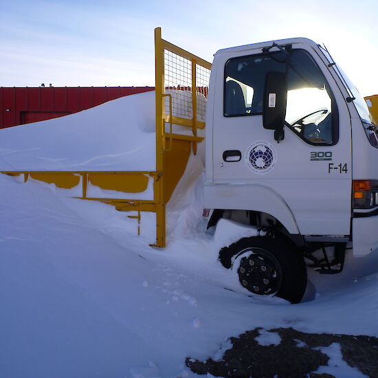 A truck which is largely buried under snow at Mawson station.