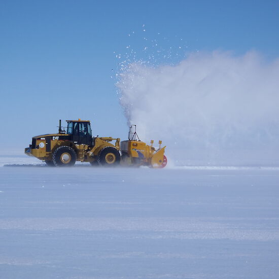 Large tracked vehicle clears snow on runway
