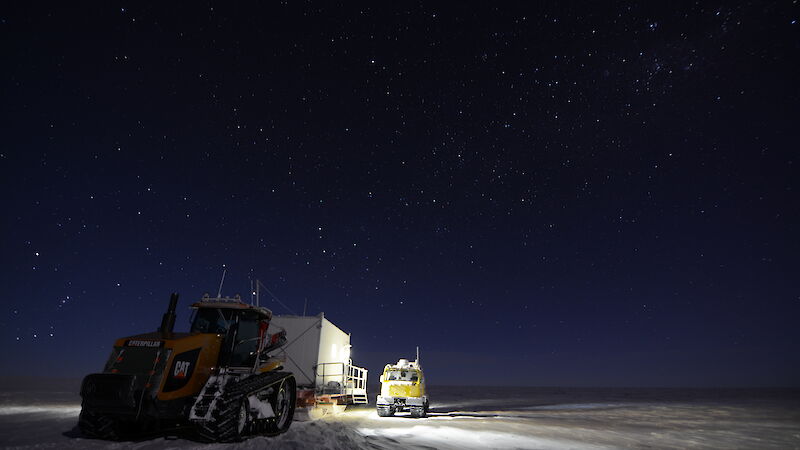 Challenger and Hägglunds vehicles parked in the moonlight underneath a wide sky of stars