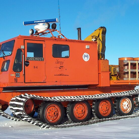 Orange vehicle with a cab for passengers and tracks.