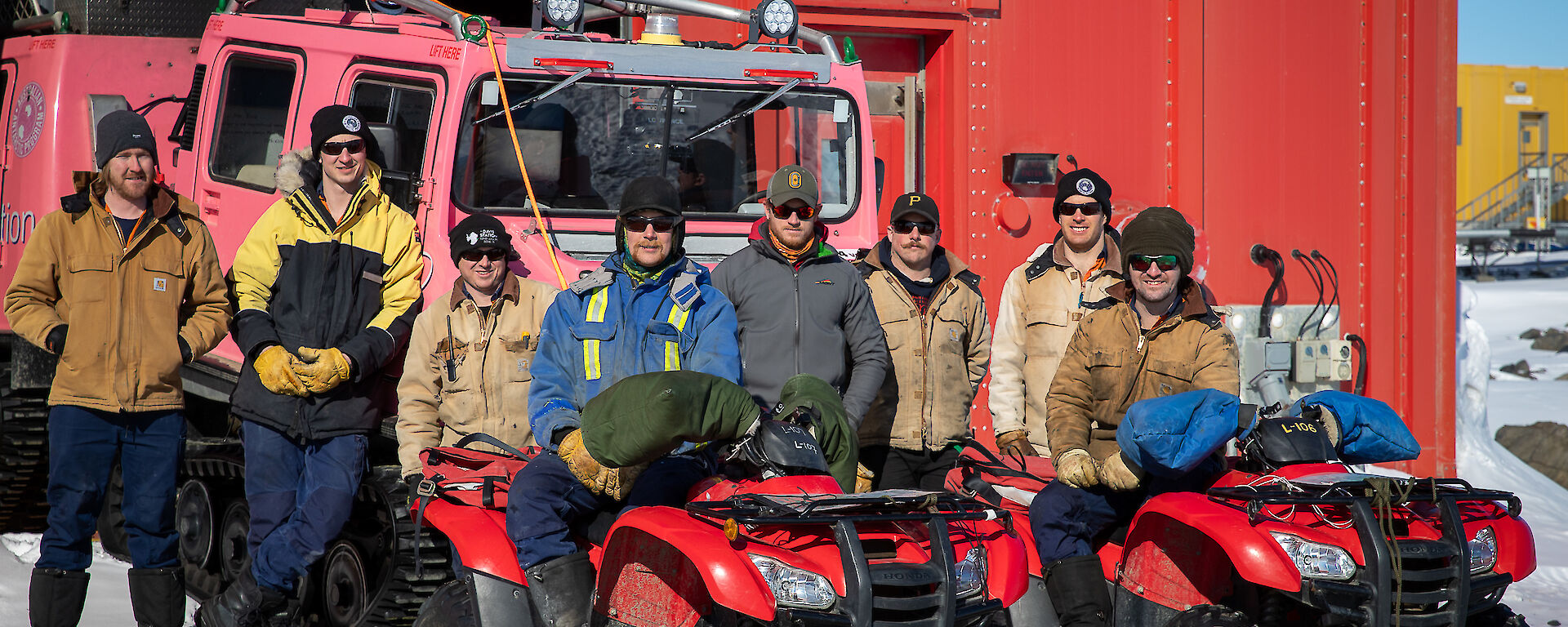 Group of expeditioners outside workshop standing near quads