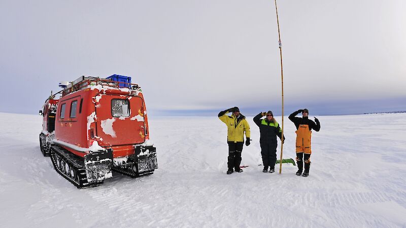 Expeditioners hold a tall cane in place
